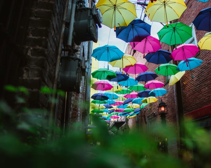 a street lined with multi colored umbrellas hanging from the ceiling