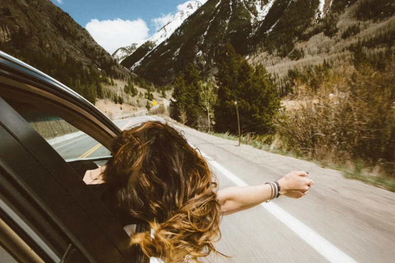 a girl drives down a mountain road in her convertible