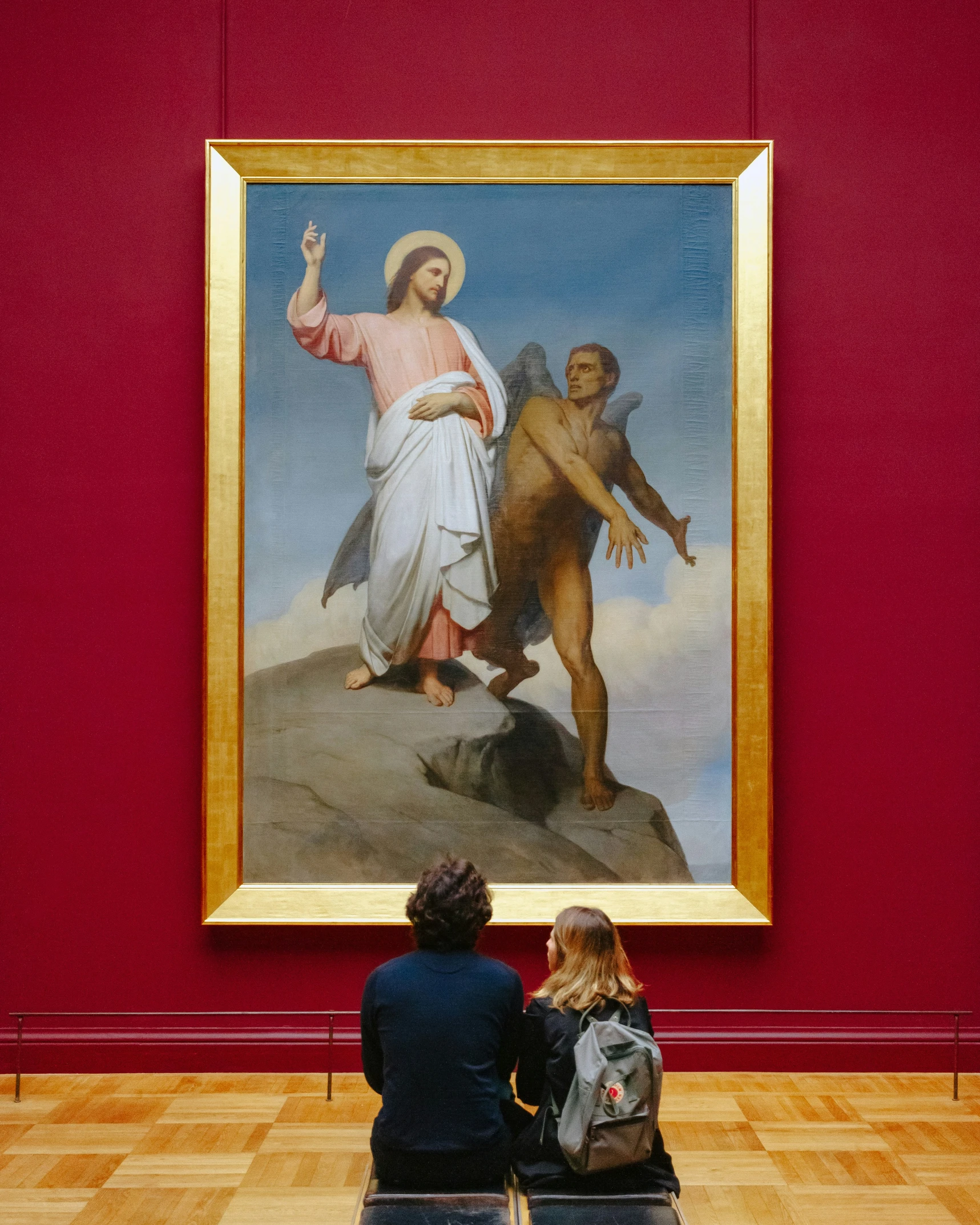 two people in front of a painting of jesus in a museum