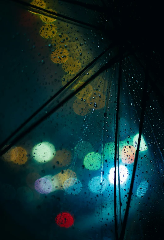 the view from inside a rain covered umbrella at night