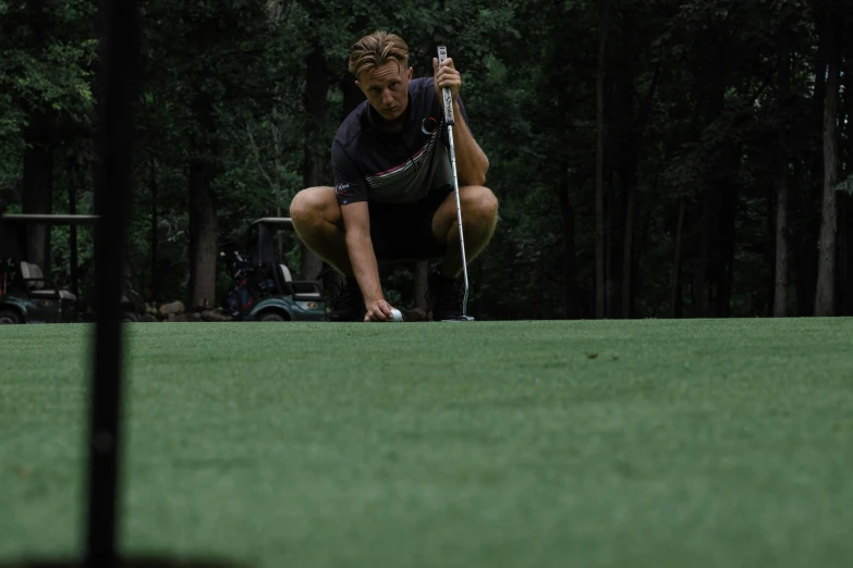 the man crouches down playing golf on the grass