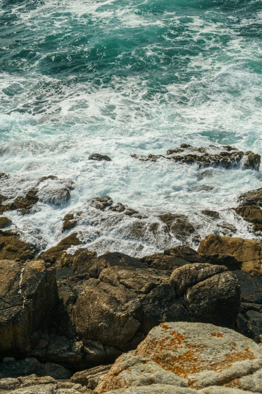 a red fire hydrant on top of rocks in front of water