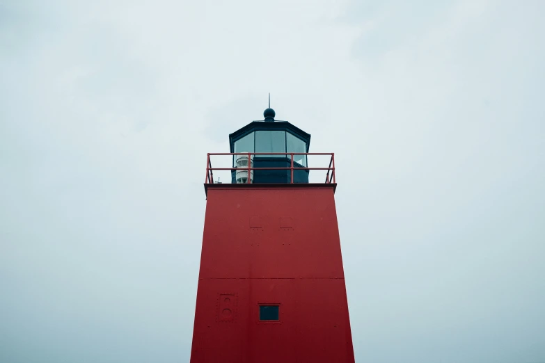 a lighthouse with a flag on the top against a cloudy sky