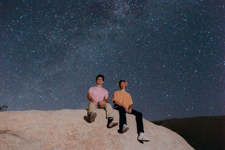 two people sitting on a white stone structure in the night