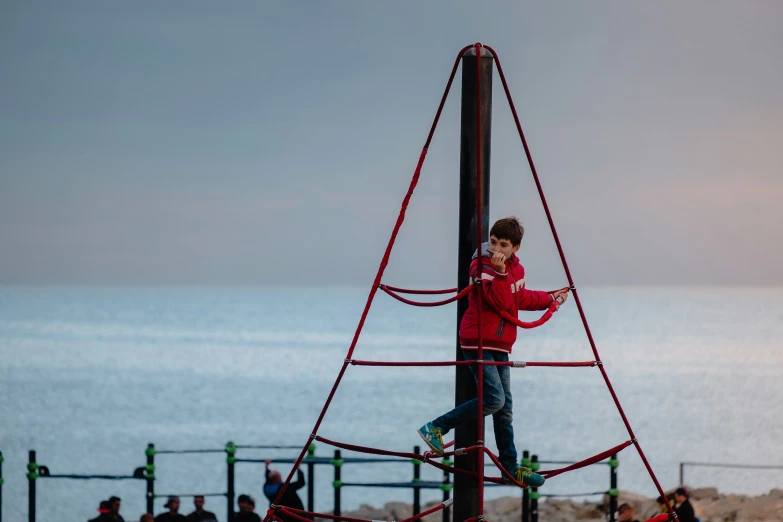 the little boy is playing on the rope climbing