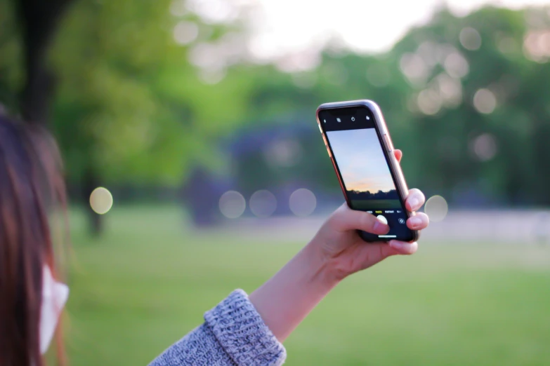 a woman is holding up her cellphone while she looks at the screen