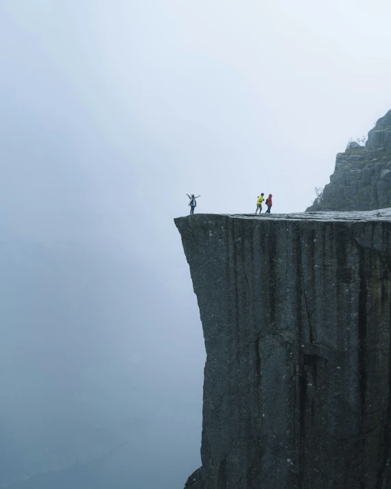 people standing on a high ledge near the edge of a cliff