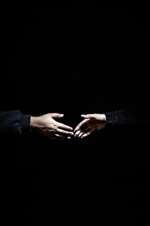 hands reaching out to each other over dark surface