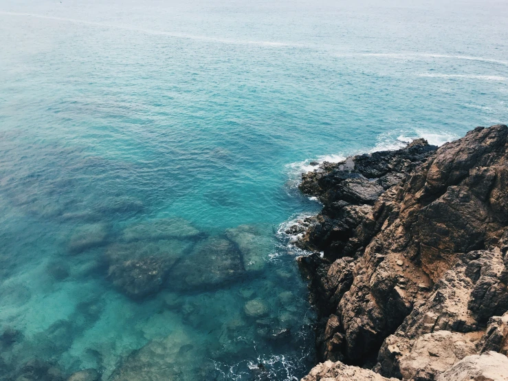 the clear water is beside some rocky cliff