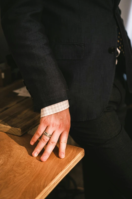 person holding their wedding ring on the wooden table