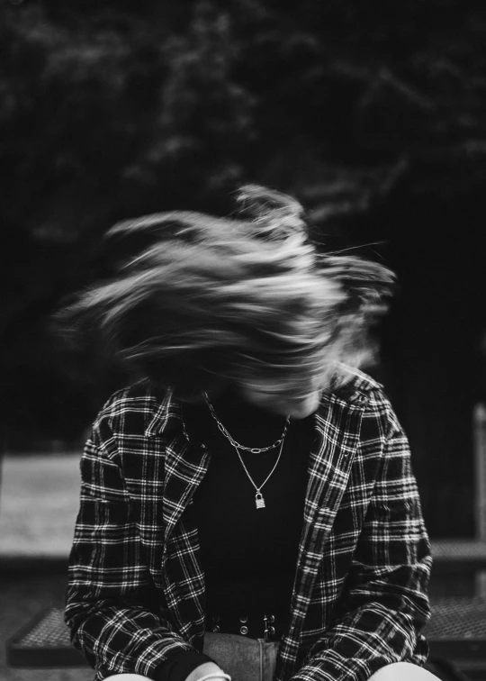 a woman sits on a bench with a book as her hair glides in the wind