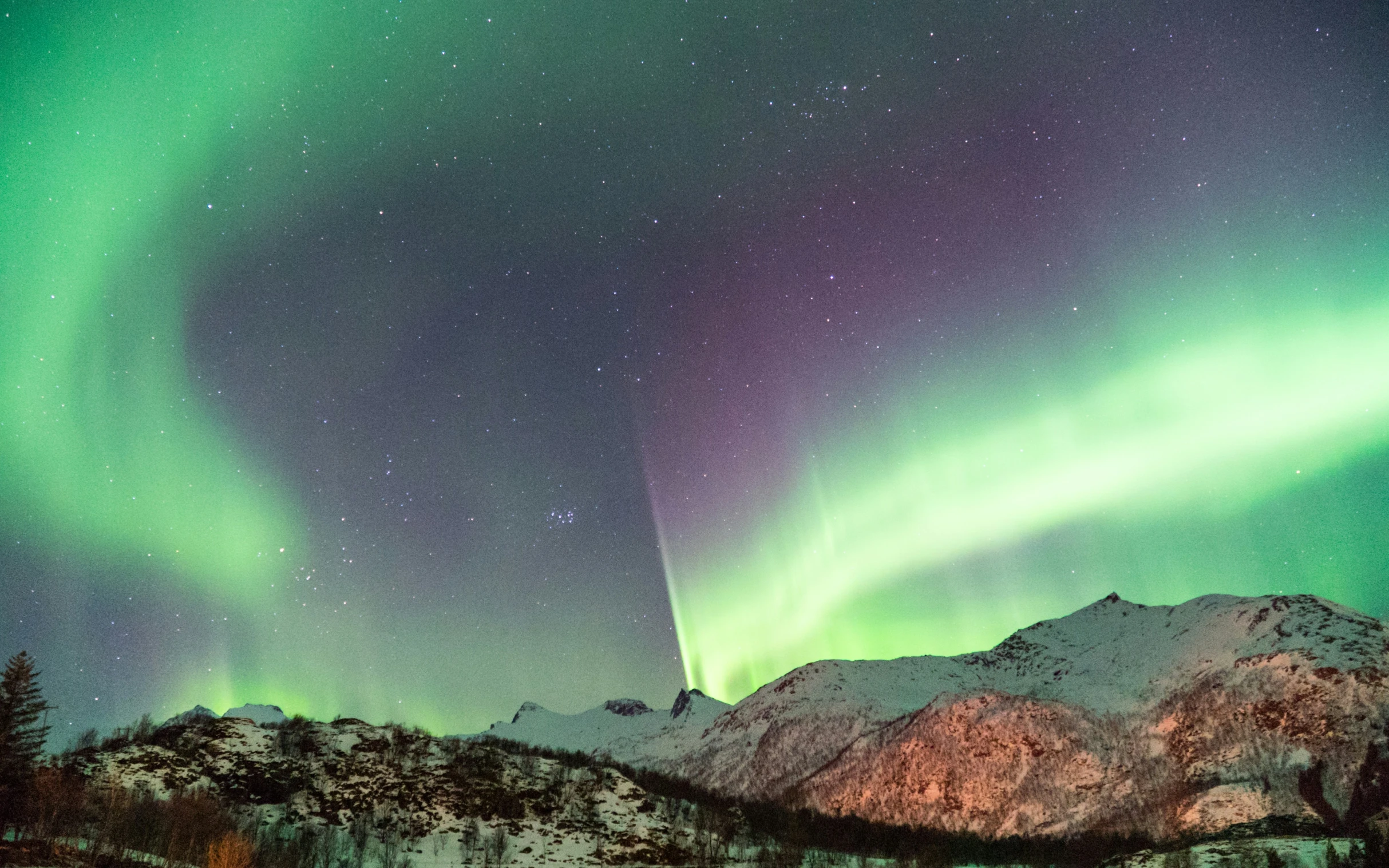 an aurora aurora bore above a mountain range with snow covered mountains in the background