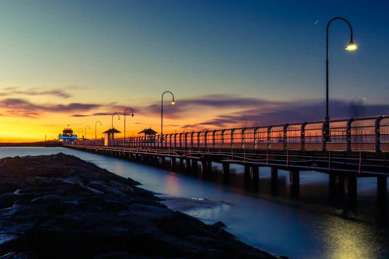 a long pier on the water at sunset