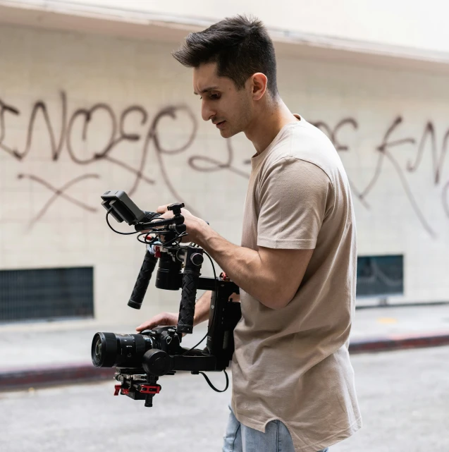 man holding onto a black object in front of some graffiti