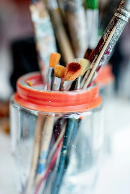 the glass jar holds many brushes and other paints