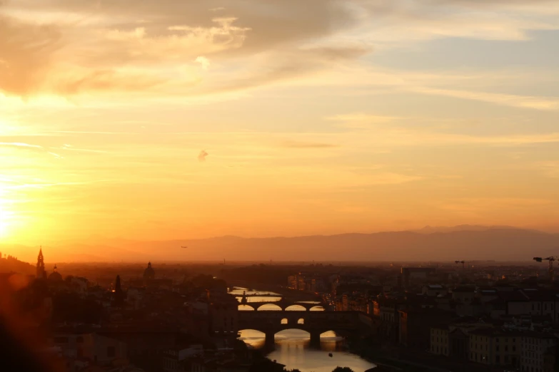 sunset with a bridge and a river, some clouds