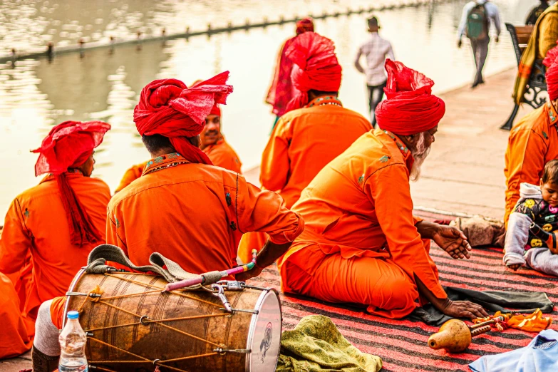 several people sitting on the ground and one person with a drum