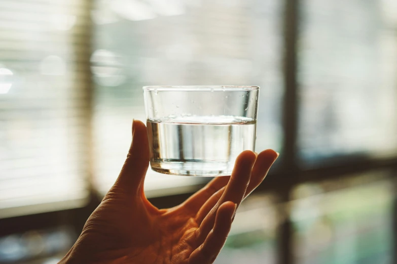 someone holding up a glass of water on their palm