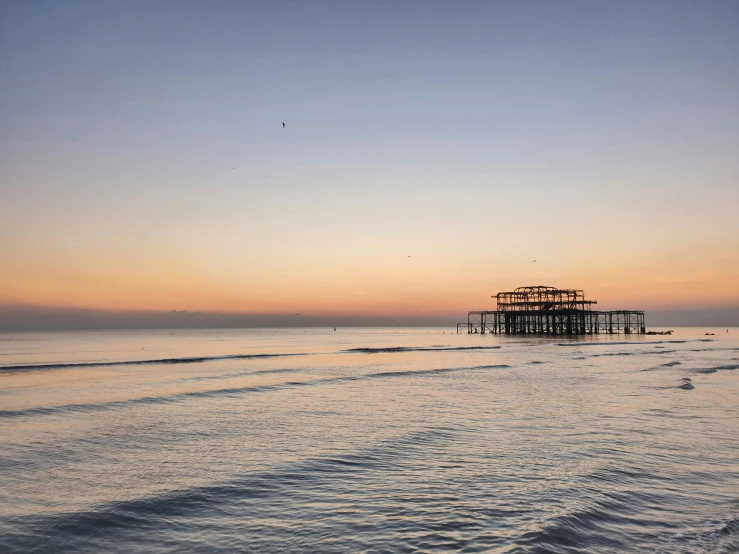 a long, wooden pier on the beach with a bird flying near it