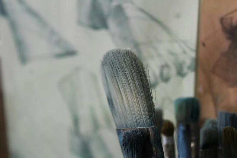 some brushes that are standing in front of a painting