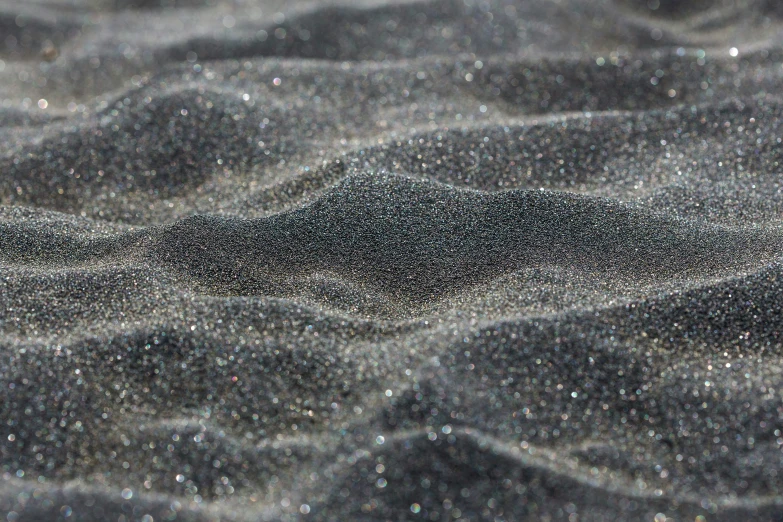 white, grey and black sand covered in small glittery flecks
