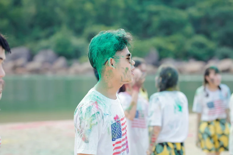 a man with green hair is standing on the beach