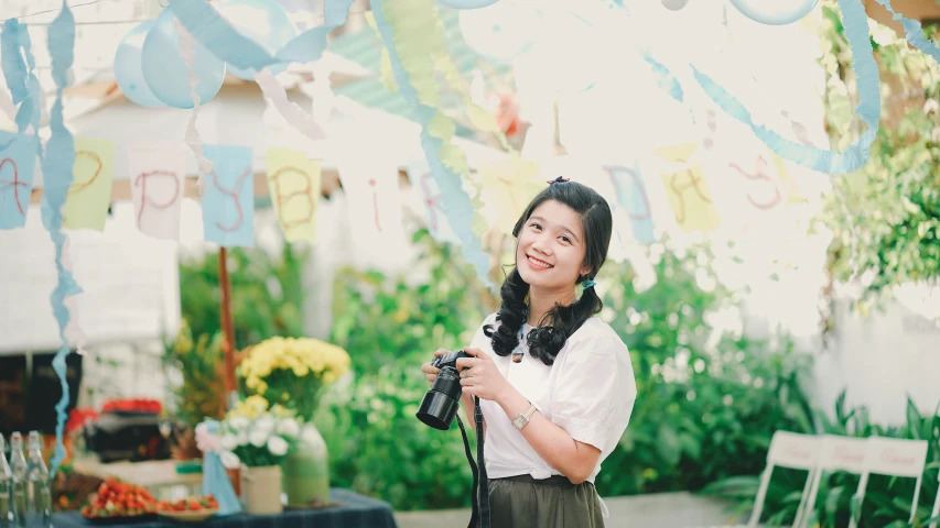 a woman in white shirt holding a camera in front of balloons