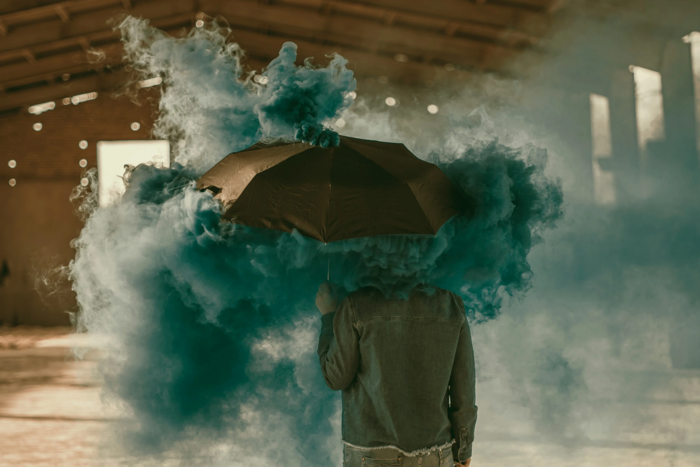 an umbrella is being held in front of the person with the green smoke behind it