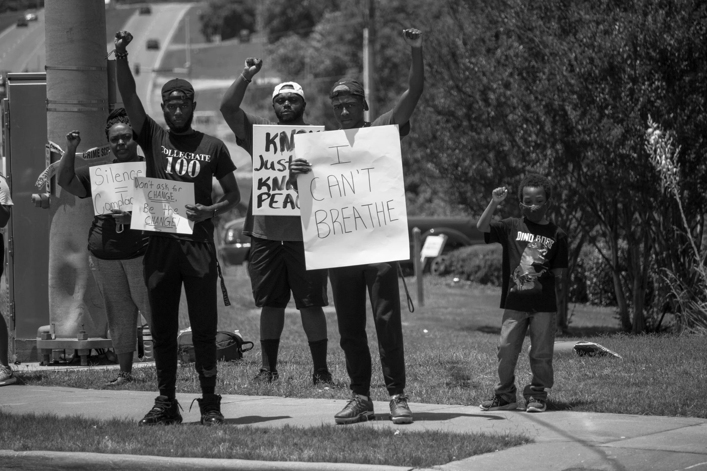 a group of young people holding signs on top of a sidewalk