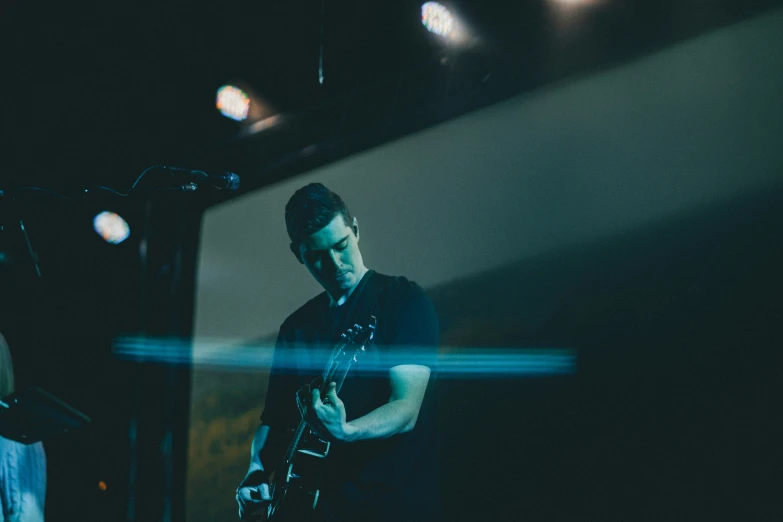 a man plays an electric guitar in a dimly lit room