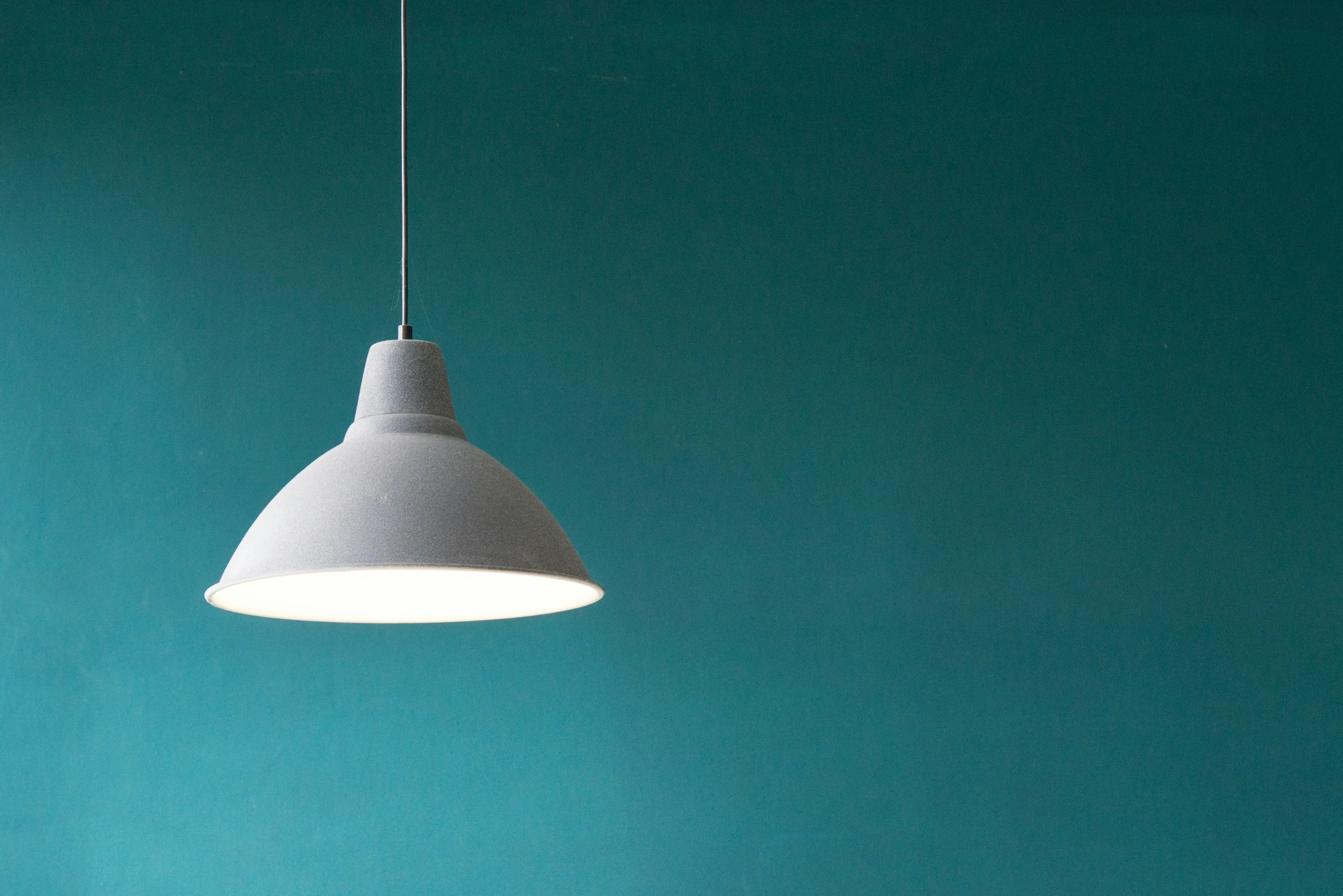 a white light hanging off the side of a blue wall