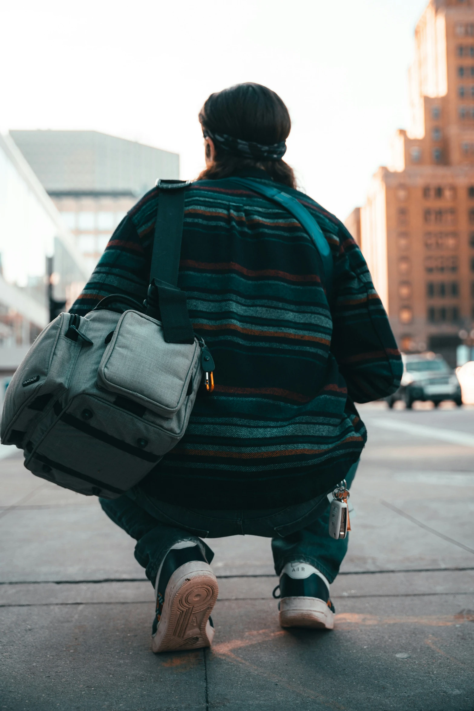 a person with a backpack squatted down on a curb