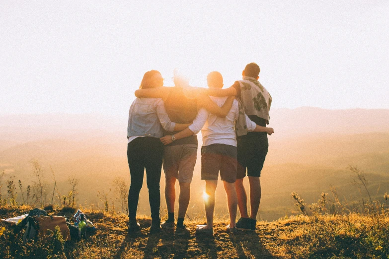 four friends are standing on top of a mountain