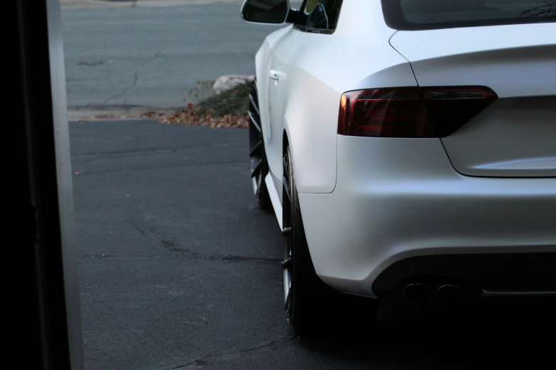 the tail end of a white car next to a street