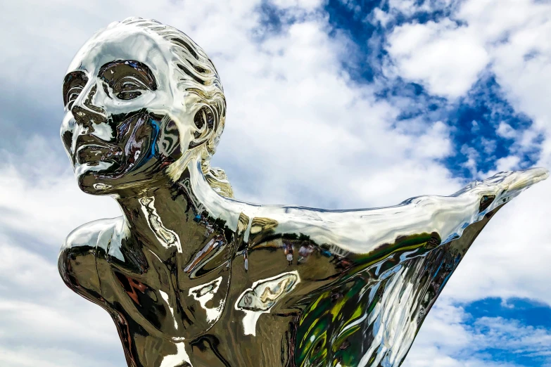 a large silver statue with a sky background