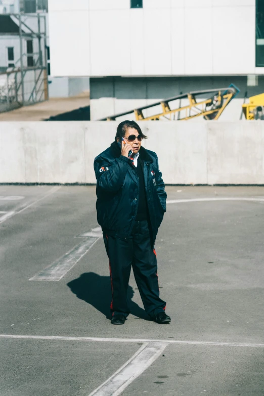 a man standing in a parking lot with his phone to his ear