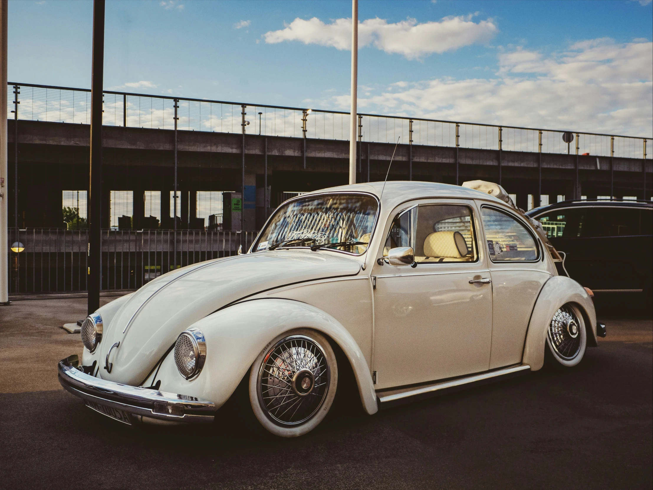 a vintage white beetle parked in the parking lot