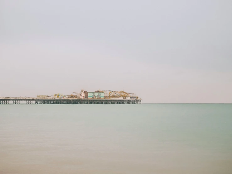 an empty beach next to a pier in the water