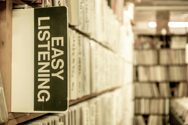 a book shelf with various books, and an upside down sign hanging from it