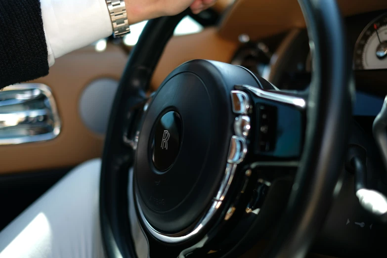two hands on a steering wheel with brown leather