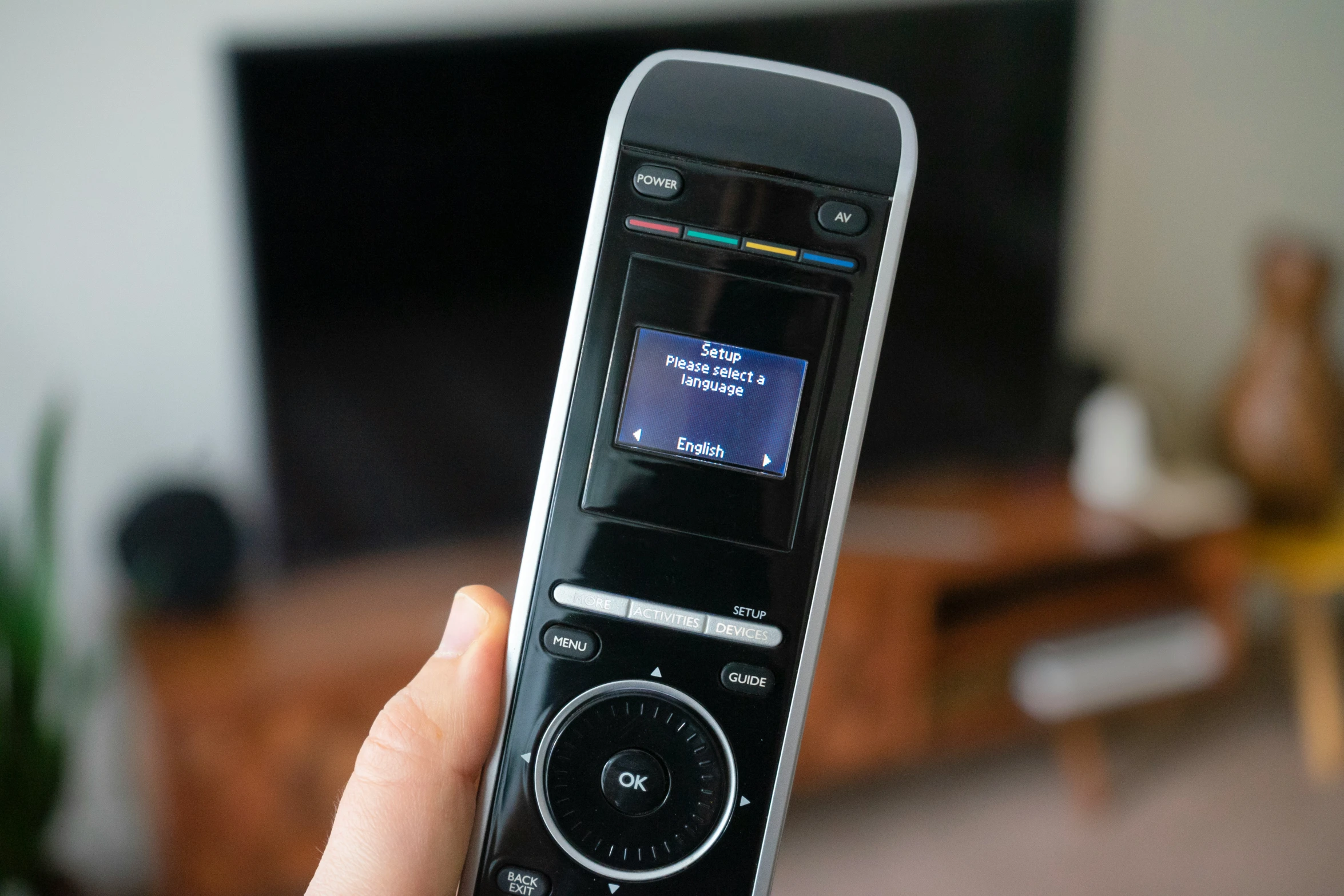 someone holding onto their flip phone in front of a tv