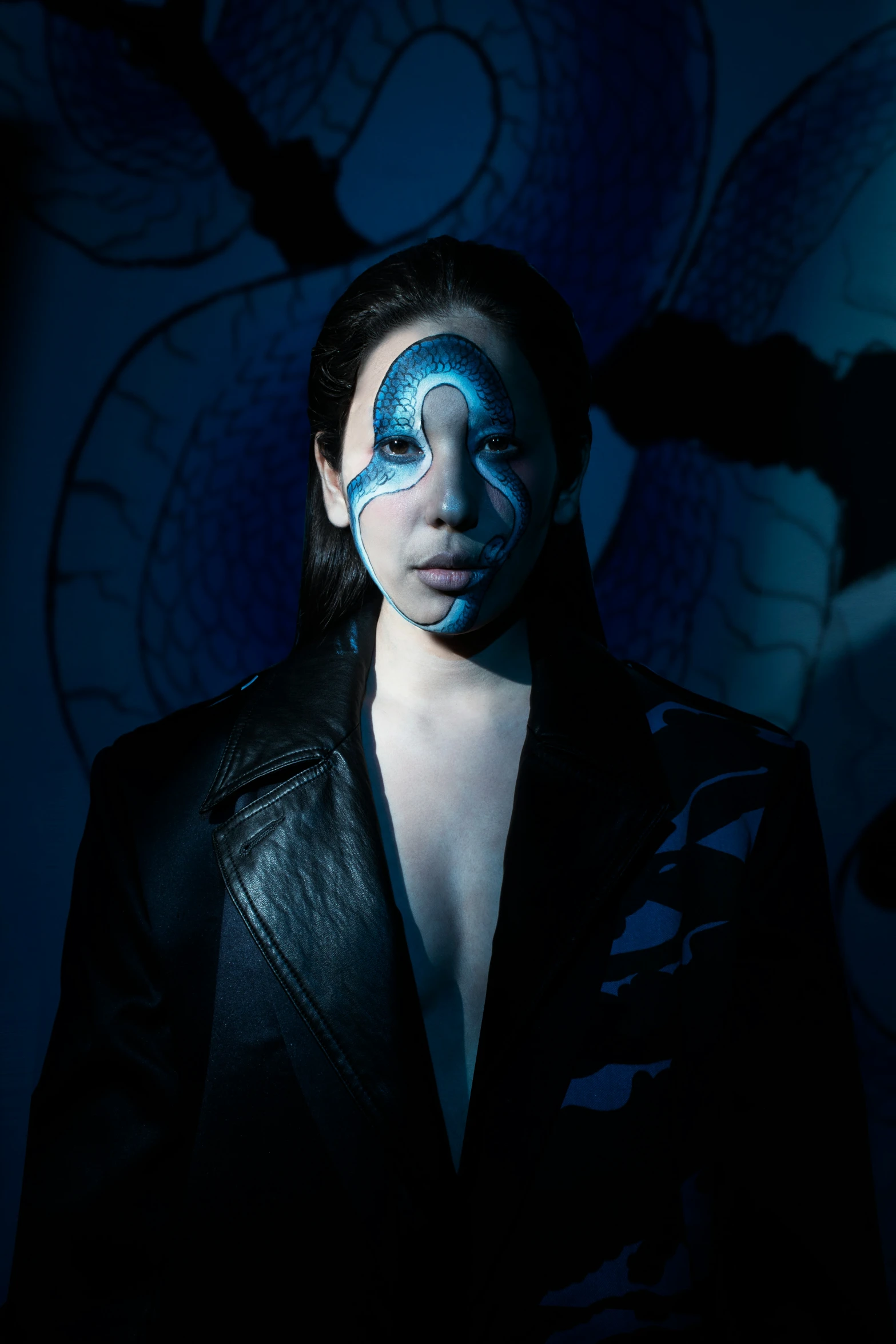 a woman in a leather jacket with blue face paint