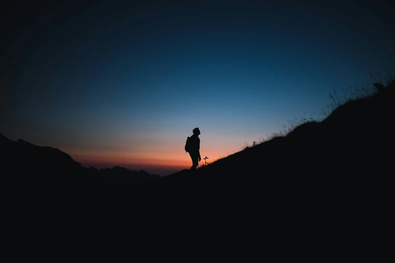 a person standing on top of a hill at sunset