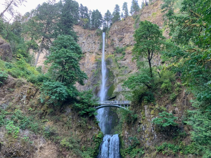 the waterfall is near a bridge over the water