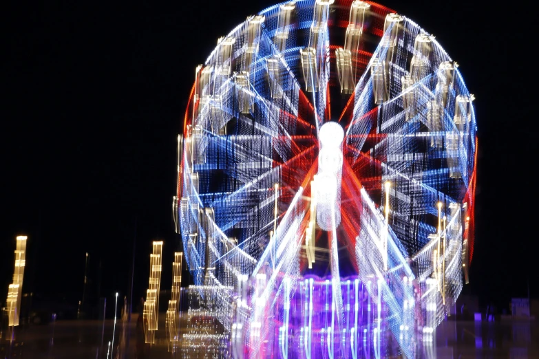 large ferris wheel lit up at night with city lights behind
