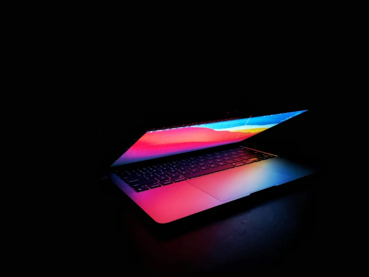 the apple macbook pro laptop on its back with rainbow tint