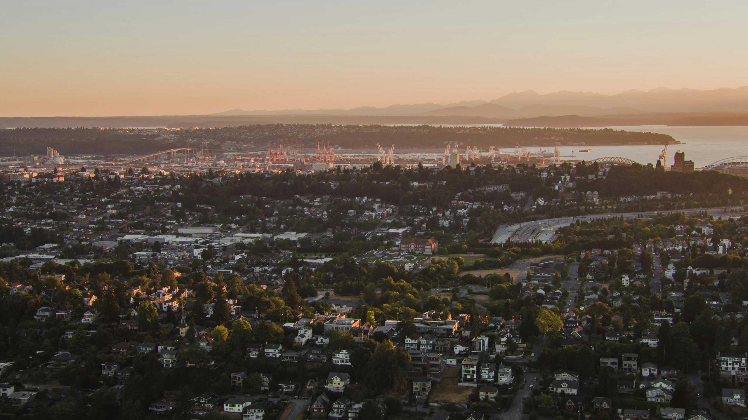 the view from a mountain overlooking a city at sunset