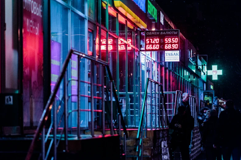 a night view of some people on the sidewalk