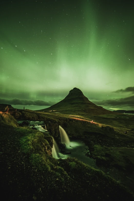 a green sky that is lit up above a mountain