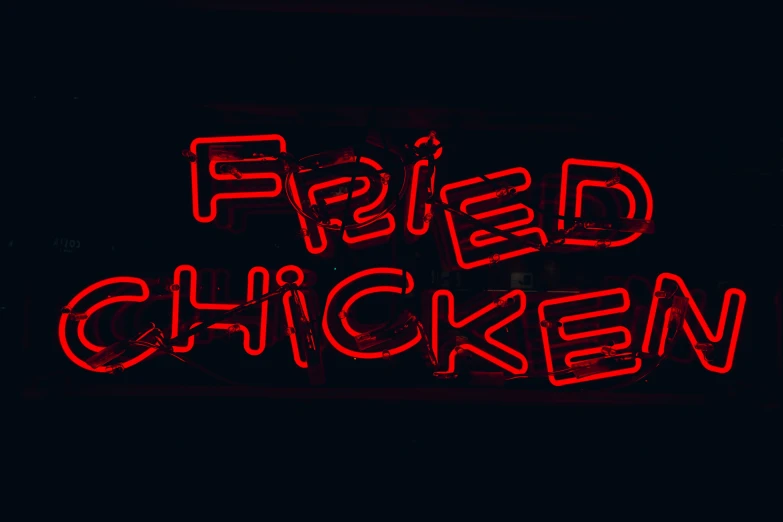 a neon sign saying fried chicken next to a building